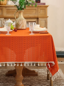 Macro detail of orange hollow lace tablecloth with delicate geometric crochet and tassels