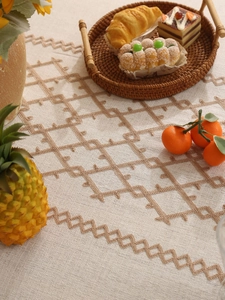 Close-up of beige linen table runner with brown geometric diamond embroidery detail