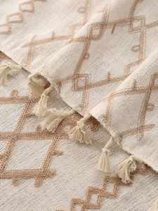 Macro shot of boho linen tablecloth featuring hand-woven tassels and geometric textures