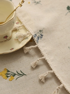 Detailed macro shot of linen embroidery tablecloth with floral patterns and fringe tassels