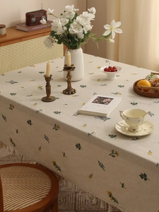 Detailed close-up of embroidered linen tablecloth with yellow floral patterns and lace tassels
