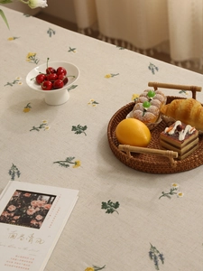 Detailed close-up of premium linen tablecloth with elegant floral embroidery and pastries