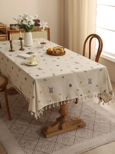 Detailed close-up of premium linen tablecloth with floral embroidery and tassel fringe