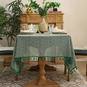 Vintage green crochet lace tablecloth with fringe trim on a rustic wooden dining table