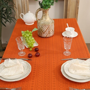Vibrant orange hollow lace tablecloth with geometric patterns on a set dining table