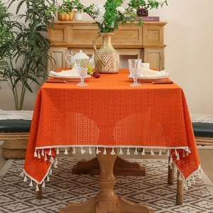 Orange lace tablecloth with tassel edges on a wooden table in a cozy home setting