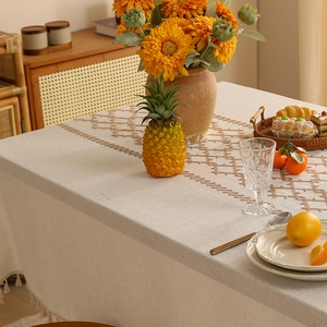 Linen tablecloth with brown diamond embroidery and tassels on a cozy dining table