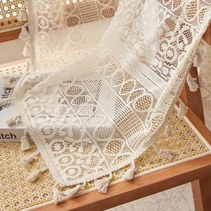 Vintage crochet lace curtain with fringe details draped over a wooden rattan chair