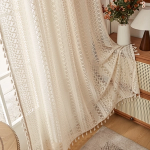 Detail of vintage beige lace curtain with floral patterns and delicate fringe tassels