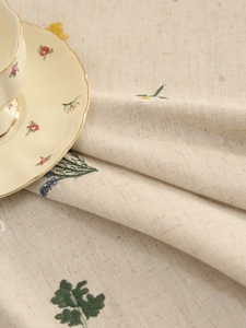Detail of linen tablecloth featuring exquisite floral embroidery and thick woven texture
