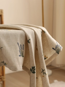 Detailed texture of beige linen tablecloth with lavender and daisy floral embroidery