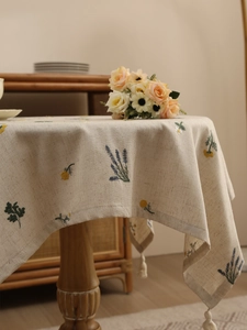 Close-up of floral embroidery and fringe tassels on beige linen tablecloth