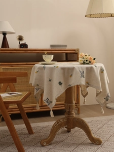 Detail of linen tablecloth with floral embroidery and white decorative tassels on edges