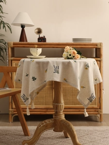 Detail of linen tablecloth with lavender floral embroidery and vintage cotton tassels