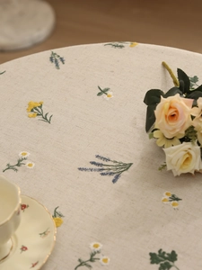 Close-up of linen tablecloth with detailed daisy embroidery and lavender floral patterns