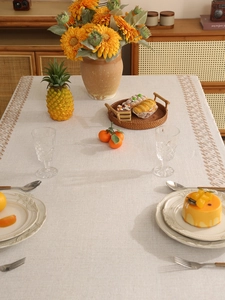 Close-up of beige linen tablecloth with geometric embroidery and elegant table setting