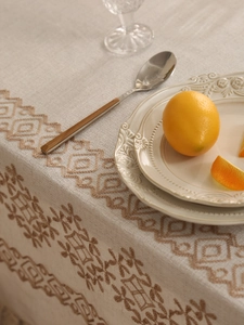 Detail of premium heavy linen tablecloth with dark brown floral embroidery and lemon styling