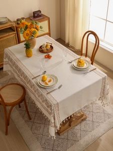Detailed texture of beige linen tablecloth with tribal patterns and handmade tassels