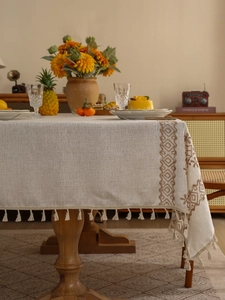 Detail of linen tablecloth featuring brown diamond embroidery and beige tassels
