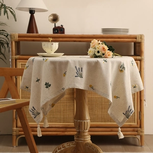 Embroidered linen tablecloth with floral patterns and tassels on a round table