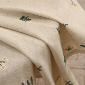 Elegant oatmeal linen tablecloth with delicate daisy floral embroidery in a macro view