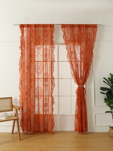 Detalle de cortina de encaje naranja con bordado floral y elegantes bordes con volantes