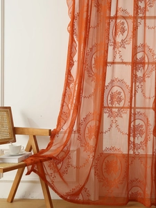 Detalle de cortinas de encaje bordado naranja con elegantes motivos florales ovalados