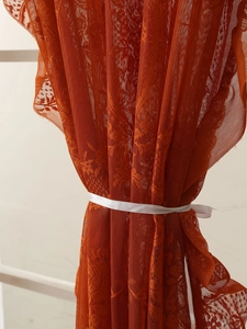 Detalle de cerca de una cortina de encaje francés naranja quemado con motivos florales