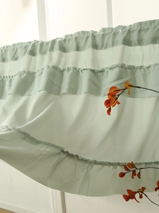 Detail of light green ruffled valance curtain showing layered fabric and delicate stitching