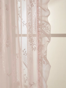 Detail of elegant floral lace curtain with ruffled edges in soft beige light