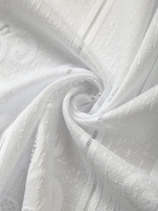 Macro shot of white lace kitchen curtain fabric with intricate mesh and floral jacquard