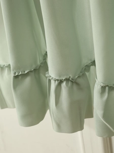 Detailed close-up of light green chiffon fabric with delicate ruffled waves and texture