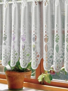 Close-up of white lace kitchen curtain with vintage crochet floral and hollow patterns