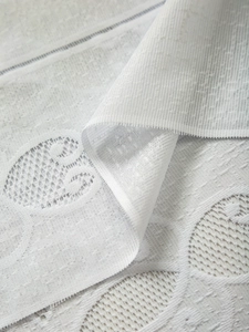 Macro view of white lace curtain fabric showing intricate hollowed-out mesh patterns