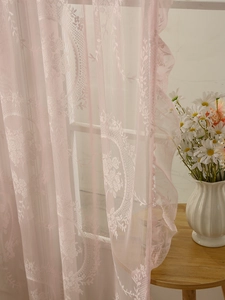 Detailed view of pink floral lace curtains with rose jacquard patterns in a cozy room