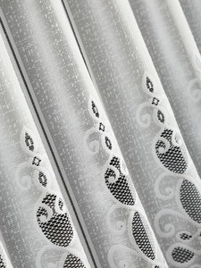 Close-up of white lace kitchen curtain with floral embroidery and mesh texture