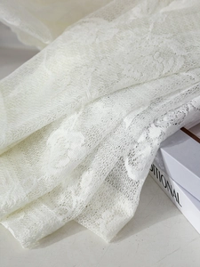 Detailed macro view of French style white lace floral fabric with intricate embroidery