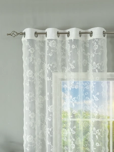 Detail of white floral lace curtain with silver grommets and translucent floral pattern