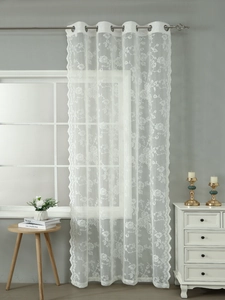 Close-up of white French lace curtain featuring floral embroidery and wavy scalloped edges
