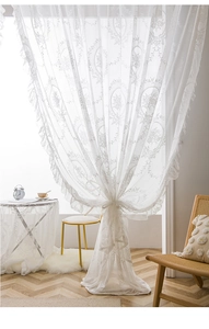Detail of white French lace curtain with floral embroidery and elegant ruffled edges