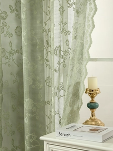 Detail of light green lace curtain showing rose floral embroidery and wavy scalloped edges