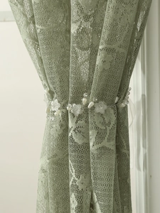 Detail of floral curtain tieback with white pearls and resin petals on lace fabric