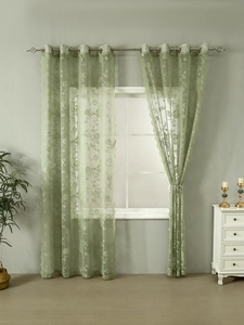 Close-up of light green lace curtain with floral pattern and silver grommet rings