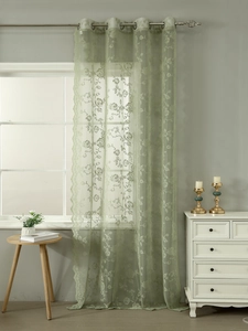 Detail of light green lace curtain with floral embroidery and metal eyelet rings