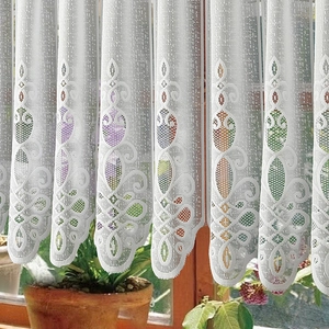 White lace cafe curtain with vintage embroidery hung in a kitchen window setting