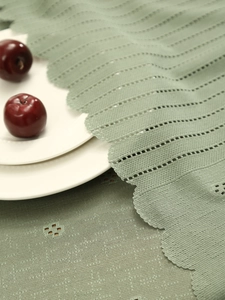 Close-up of sage green woven tablecloth with hollow lace edges and scalloped trim
