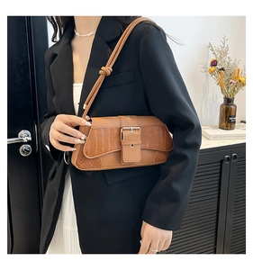 Detail of brown croc-texture shoulder bag with gold buckle on black blazer