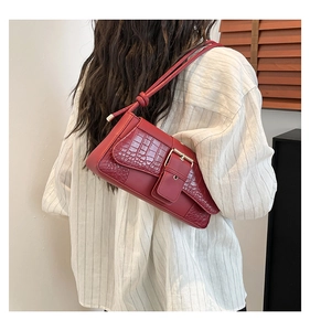 Detail of burgundy baguette bag with croc-embossed texture and golden square buckle clasp