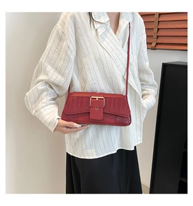 Détail du sac à bandoulière rouge motif crocodile avec une boucle en métal doré