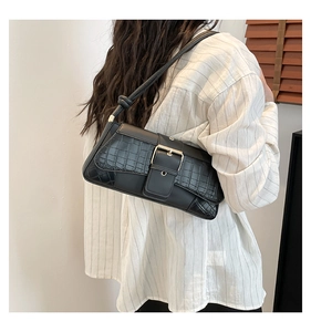 Detail of black crocodile texture bag with gold buckle and stylish knotted shoulder strap